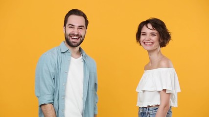 Wall Mural - Young fun couple friends bearded guy girl 20s in casual clothes posing isolated on yellow background studio. People emotions lifestyle concept Meeting together greeting giving high five clapping hands