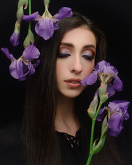 Wall Mural - Beautiful young caucasian brunette woman long hair trendy style with closed eyes irises flower black background for makeup artist portfolio in film effect colors