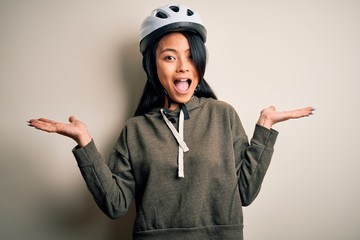 Wall Mural - Young beautiful chinese woman wearing bike helmet over isolated white background celebrating crazy and amazed for success with arms raised and open eyes screaming excited. Winner concept