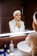 © Yakobchuk Olena - Jolly pretty lady doing beauty procedures in front of mirror
