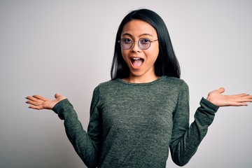 Wall Mural - Young beautiful chinese woman wearing glasses and t-shirt over isolated white background celebrating crazy and amazed for success with arms raised and open eyes screaming excited. Winner concept