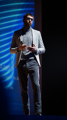 Aufkleber - Successful Male Speaker Stands on Stage, Greets Audience and Does Presentation of the Technological Product, Shows Infographics, Statistics Animation on Screen. Start-up Conference. Vertical Photo.