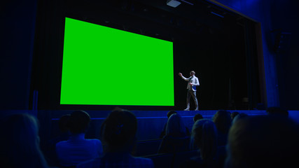 keynote speaker announces new product to the audience, behind him movie theater with green screen, m