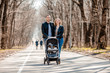 © Tina kids photo - young family walk in the park in the spring with a toddler in a stroller. Happy parents