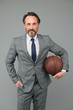 © be free - Ambitious coach. Business coach hold basketball ball. Basketball coach grey background. Confident coach or teacher in formalwear. Strategy and management. Professional at training