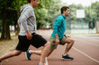 © JustLife - Young men exercising on a race track. Two young friends training outdoors.