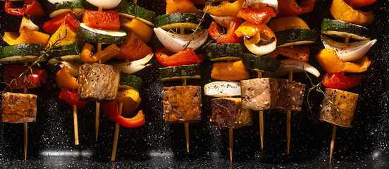 banner of vegan kebabs of vegetables and smoked tofu, in a baking sheet, ready for baking in the oven