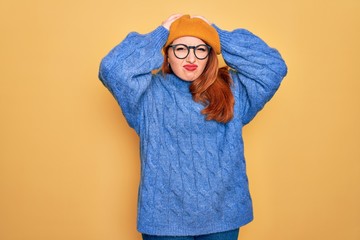 Wall Mural - Young beautiful redhead woman wearing french beret and glasses over yellow background suffering from headache desperate and stressed because pain and migraine. Hands on head.