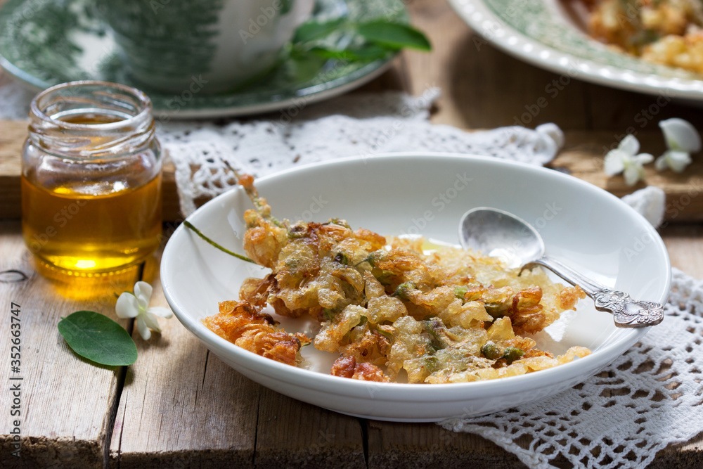 Robinia fritters served with tea and honey on a wooden table. Rustic style.