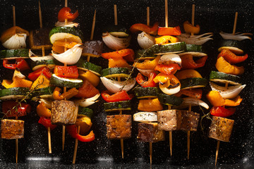 vegan kebabs of vegetables and smoked tofu, in a baking sheet, ready for baking in the oven