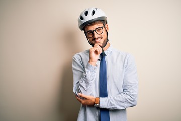 Wall Mural - Young businessman wearing glasses and bike helmet standing over isolated white bakground looking confident at the camera with smile with crossed arms and hand raised on chin. Thinking positive.