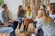 © Roman - young responsive members of anonymous club of alcoholics sit listening and supporting girl with yellow hair, she talk heartbreaking story