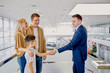 © Roman - affable caucasian consultant shake hands to child who came with parents to choose new car in dealership