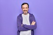 © Krakenimages.com - Middle age handsome sporty man wearing casual purple sweatshirt over isolated background happy face smiling with crossed arms looking at the camera. Positive person.