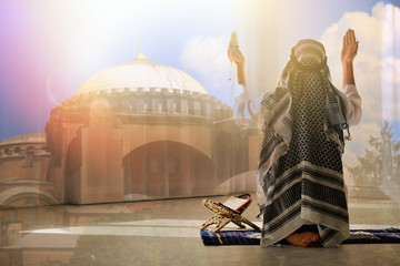 Double exposure of Muslim man praying and mosque