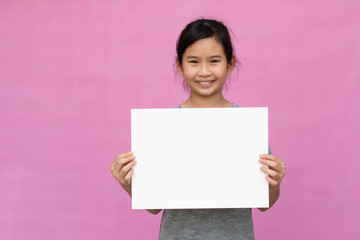 Little asian girl holding white paper isolated on pink background.