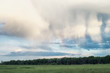 Fluffy clouds and rainbow over the forest. Landscape of spring forested valley and beautiful cloudy sky