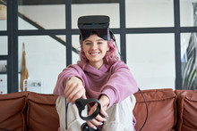 Happy Hipster Teen Girl Pink Hair Wear Vr Glasses Headset Hold Controllers Sit On Sofa Look At Camera. Digital Innovation Video Game, Virtual Reality 3D 360 Video App Education Entertainment. Portrait