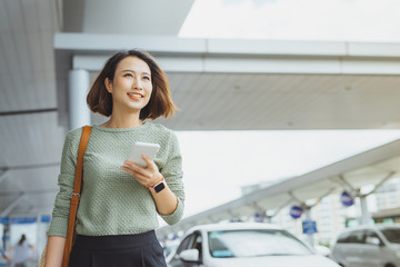 Young businesswoman using phone to check her flight when standing outside.