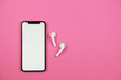 © reddish - Mobile phone with wireless headphones on pink background.