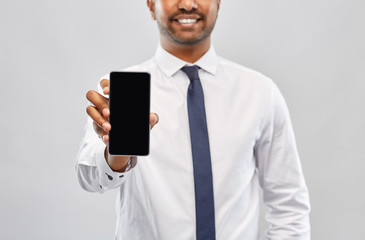 Sticker - business, technology and people concept - close up of smiling indian businessman showing black smartphone screen over grey background