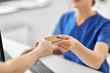 © Syda Productions - medicine, people and healthcare concept - close up of patient giving female doctor or nurse insurance or credit card card at hospital