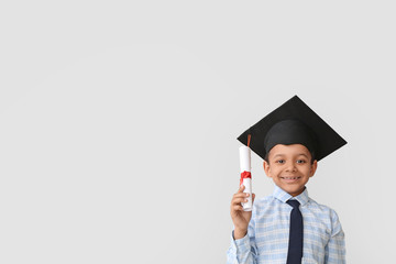 Wall Mural - Little African-American boy in graduation hat and with diploma on grey background