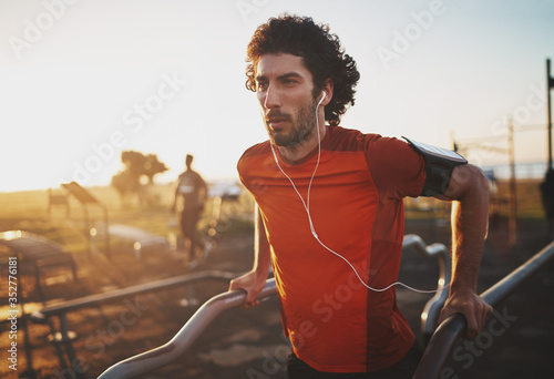 Cuadros en Lienzo Portrait of an athletic young man listening to music on earphones doing exercise