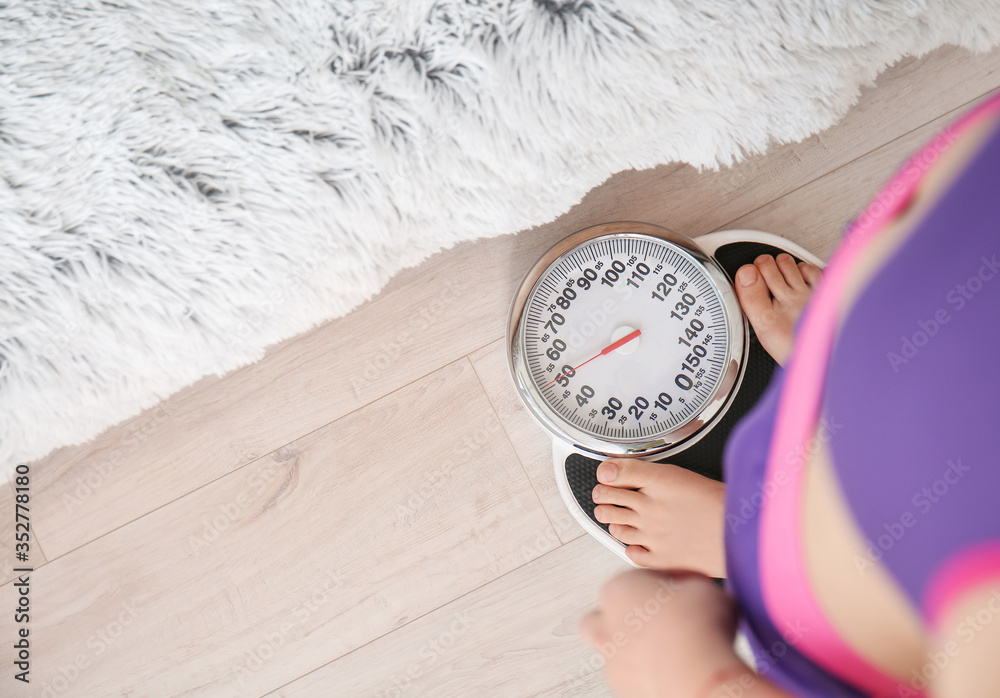 Young woman measuring her weight at home
