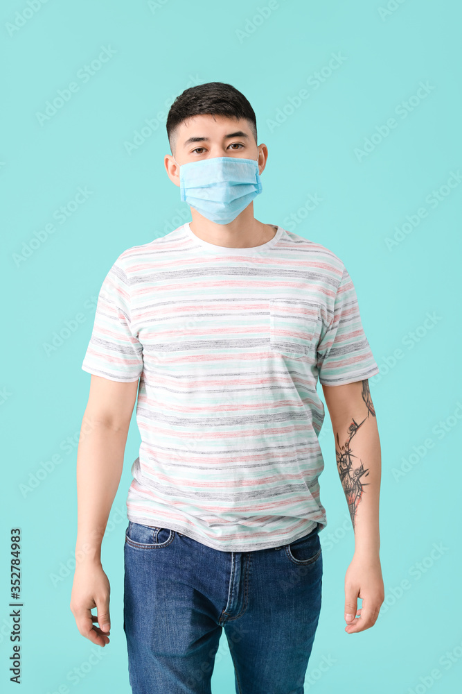Young man wearing protective mask on color background. Concept of coronavirus epidemic