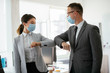 © JustLife - Businessman and businesswoman with medical mask in office. Greetings in Covid-19 time.