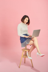 Wall Mural - Young Asian woman using laptop while sitting on chair.