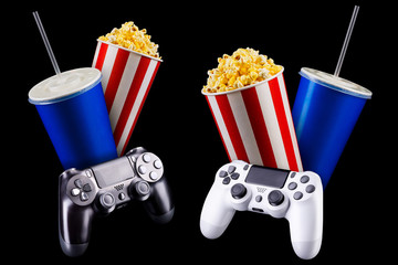 Flying popcorn, cup of soft drink and video game joystick isolated on black