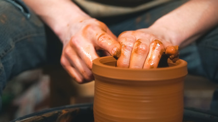 Wall Mural - Potter works with clay on wheel in workshop.