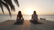 © Alexander Belinskiy - Two women warm up before practicing yoga at seaside at sunset