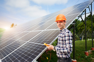 Wall Mural - Male engineer with a sensor in his hands, looking to the camera near the solar panels which reflect the rays of the sun under the blue sky. Solar in flat style on green background. Power station