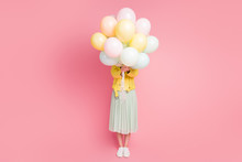 Full Length Photo Of Funny Playful Lady Hold Hands Many Air Balloons Hiding Facial Expression Wear Yellow Leather Jacket Green Long Skirt Shoes Isolated Pastel Pink Color Background