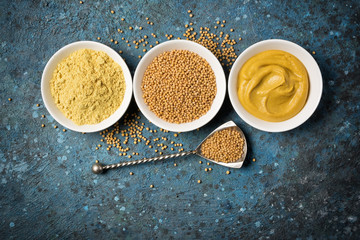 Wall Mural - Set of yellow mustard sauce, powder and seeds in small bowls with silver spoon