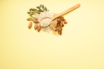 Two spoons of different sizes are filled with oatmeal and golden flax, raisins, almonds, pumpkin seeds. Healthy breakfast, proper nutrition, diet.