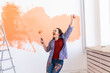 © satura_ - Renovation, redecoration and repair concept - Dancing funny woman painting wall in new home.
