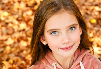 autumn portrait of adorable smiling little girl child preteen in the park