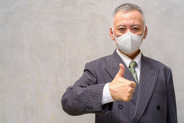 Poster - Mature Japanese businessman with mask giving thumbs up outdoors