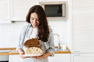 Image of happy beautiful woman smiling while showing bread on camera