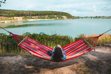 Wall Mural - woman laying on hammock enjoying the view of summer lake