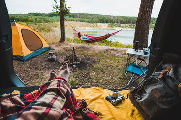 Wall Mural - person view couple resting at camping woman laying in hammock with beautiful view of forest lake