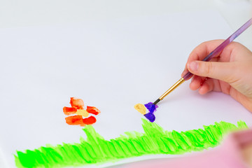 Wall Mural - Child is drawing flowers by watercolors on white paper. Concept of Earth day.