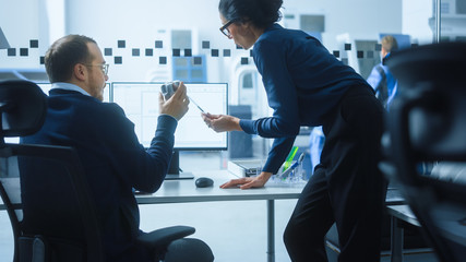 Modern Factory: Female Project Supervisor Talks to a Male Industrial Engineer who Works on Computer. They use CAD Software for Design, Development. High-Tech Industrial Facility.