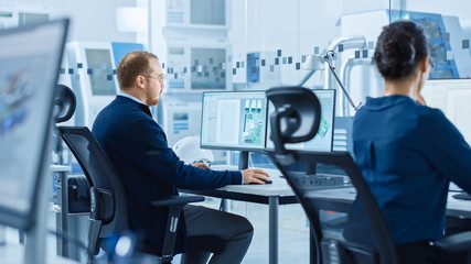 Poster - Electronics Factory: Male Electrical Engineer Holds PCB Prototype, Works on Computer, uses CAD Software to Develop Microchips, Semiconductor and Telecommunications Equipment. Manufacturing Facility