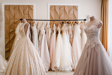 Assortment of dresses hanging on a hanger on the background studio. Fashion wedding trends. Interior of wedding shop.