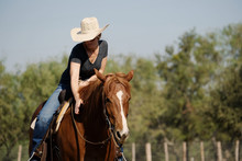 Western Lifestyle With Cowgirl In Cowboy Hat Riding Horseback During Summer Outdoors.